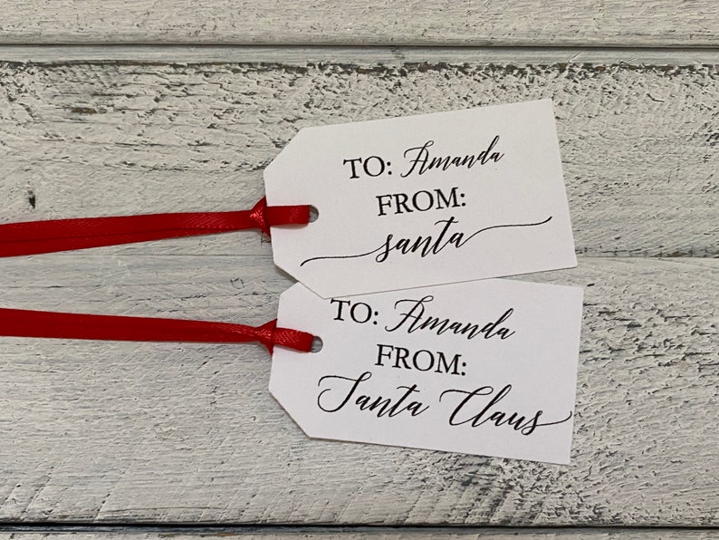 May include: Two white gift tags with black text. The top tag says "TO: Amanda FROM: santa". The bottom tag says "TO: Amanda FROM: Santa Claus".