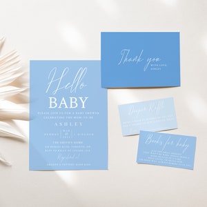 May include: Blue and white baby shower invitation with the text "Hello Baby" and details for the event.  The invitation includes the name Ashley, the date, time, and location.  There are also thank you cards and cards for a diaper raffle and books for baby.