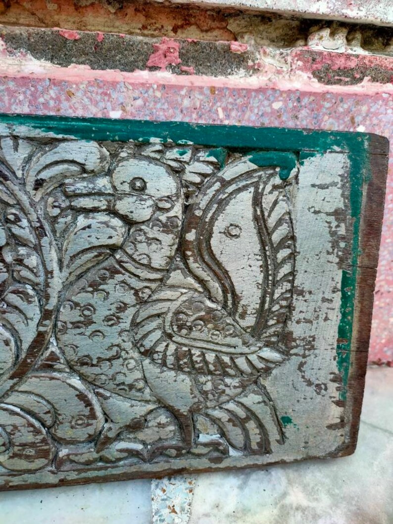 May include: A carved wooden panel with a green border, featuring a detailed design of two birds with intricate feathers and a faded silver paint finish.