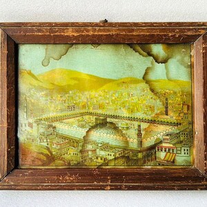 Puede incluir: Una impresi&oacute;n enmarcada vintage que representa una ilustraci&oacute;n detallada de una ciudad con una mezquita en el centro. La impresi&oacute;n est&aacute; en un marco de madera con un acabado marr&oacute;n. La ilustraci&oacute;n est&aacute; en tonos de amarillo, marr&oacute;n y verde.