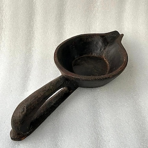 May include: A dark brown wooden bowl with a long handle. The bowl is carved from a single piece of wood and has a smooth, polished finish.