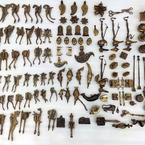 May include: A collection of over 100 antique brass ornaments, including animal figures, bells, and other decorative pieces. The ornaments are arranged in rows on a white surface.