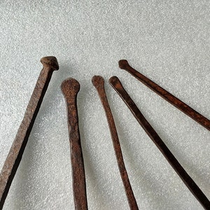 以下が含まれることがあります： 白い表面に放射状に配置された、先のとがった先端を持つさびた金属製の道具が6つあります。