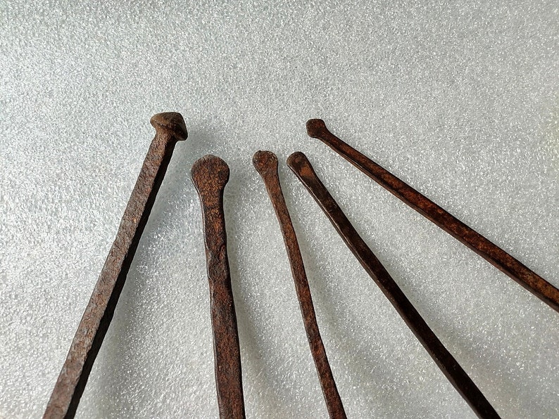 以下が含まれることがあります： 白い表面に放射状に配置された、先のとがった先端を持つさびた金属製の道具が6つあります。