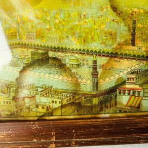 Puede incluir: Una impresi&oacute;n enmarcada vintage que representa una ilustraci&oacute;n detallada de una ciudad con una mezquita en el centro. La impresi&oacute;n est&aacute; en tonos amarillos, verdes y marrones, con un marco de madera.