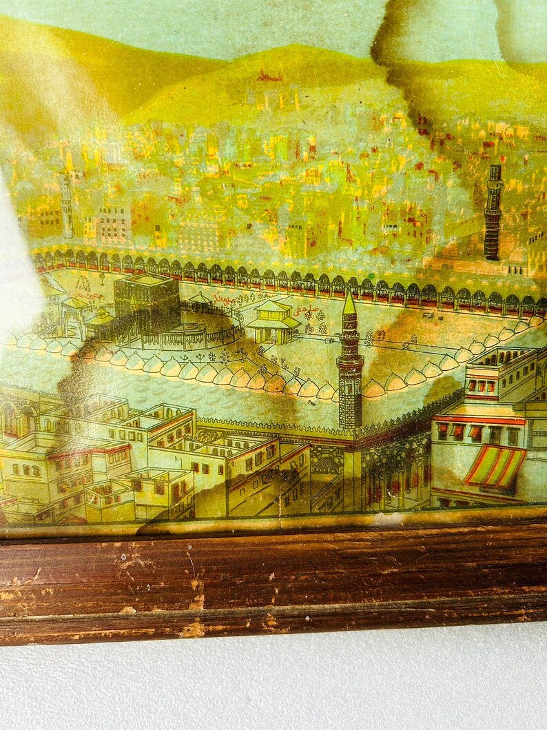 Puede incluir: Una impresi&oacute;n enmarcada vintage que representa una ilustraci&oacute;n detallada de una ciudad con una mezquita en el centro. La impresi&oacute;n est&aacute; en tonos amarillos, verdes y marrones, con un marco de madera.