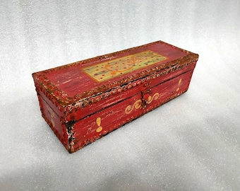 May include: A rectangular, red wooden box with gold detailing and a decorative border. The lid has a painted design with gold and yellow details. The box is secured with a metal clasp and has painted text on the side.