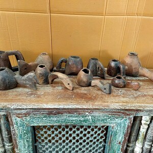 Peut inclure: Une collection de petits récipients et cuillères en bois brun foncé aux formes variées, certains dotés de poignées et d'autres avec des extensions allongées en forme de queue. Ces objets artisanaux présentent des textures de grain de bois naturel.