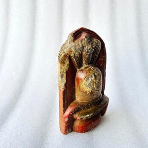 Puede incluir: Una peque&ntilde;a escultura de piedra tallada a mano de una deidad con un acabado de pintura roja y dorada. La escultura est&aacute; en posici&oacute;n de pie con una corona en la cabeza.