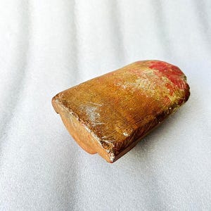 Puede incluir: Un peque&ntilde;o bloque rectangular de madera de color marr&oacute;n rojizo con una superficie lisa y ligeramente texturizada.