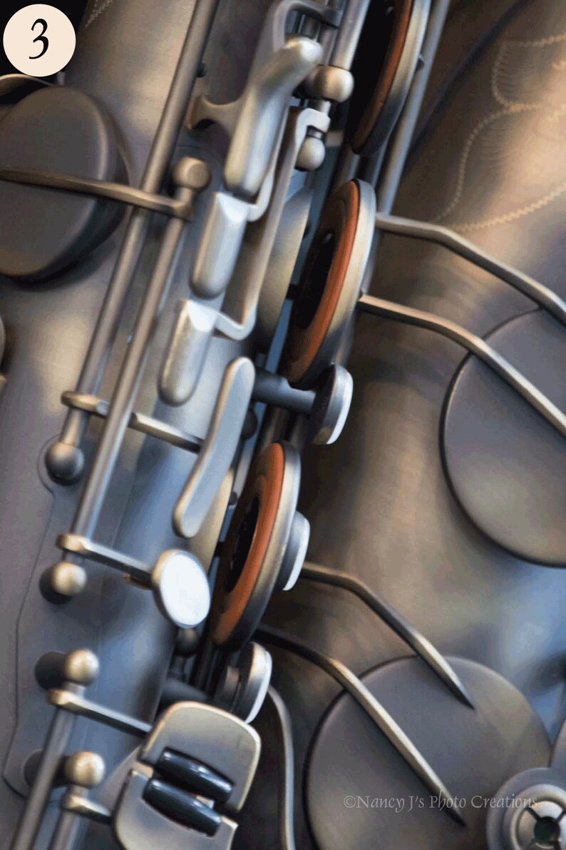 May include: Close-up of a silver saxophone with brown key pads. The saxophone is made of metal and has a shiny finish.