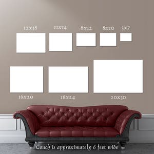 May include: A beige wall with a couch in front of it. The wall has nine white frames with different dimensions, each labeled with the dimensions in inches. The frames are arranged in three rows. The couch is red with a tufted back and is approximately 6 feet wide.
