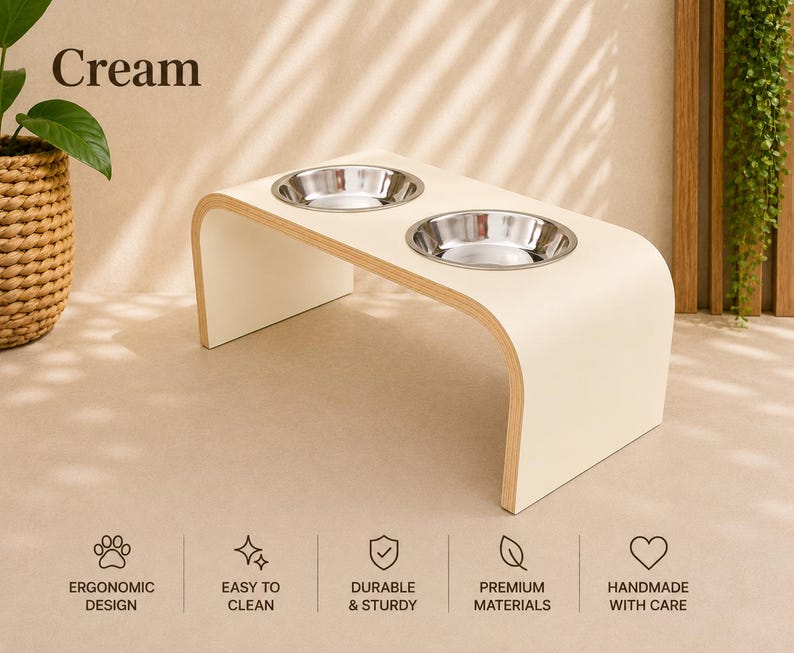 Cream raised dog bowl stand with stainless steel bowls, handmade elevated wooden pet feeder in a bright modern home, elegant feeding station for dogs and cats.