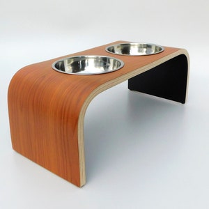 Angled view of Cherrywood finish on topside with black on underside double raised pet feeder with stainless steel bowls and natural wood edge finish.