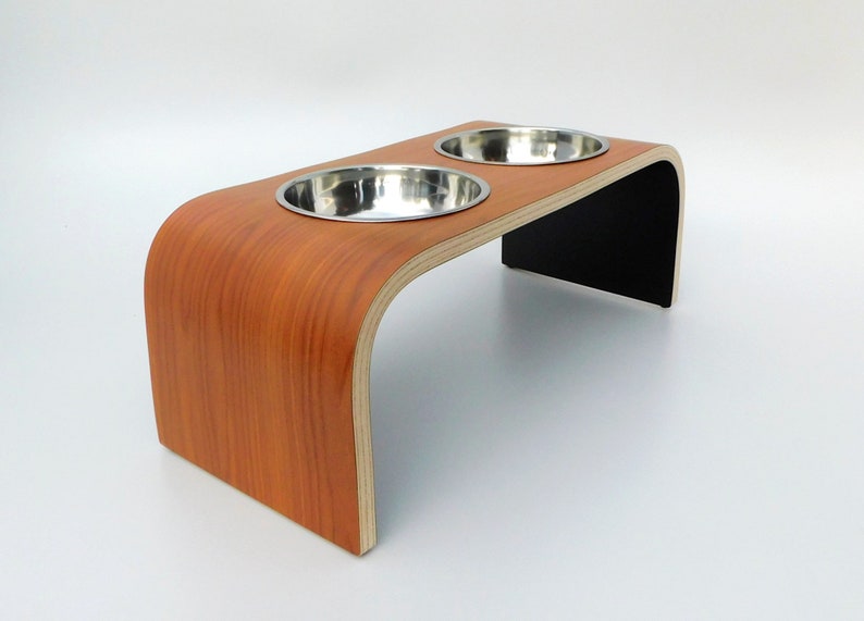 Angled view of Cherrywood finish on topside with black on underside double raised pet feeder with stainless steel bowls and natural wood edge finish.