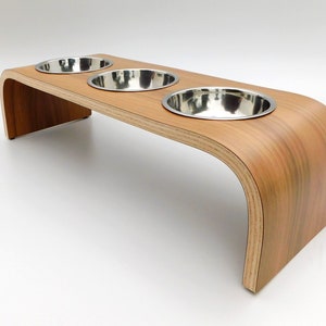 Angled view of our triple bowl raised dog feeder in a walnut finish on a white background with three stainless steel bowls and showing the natural wood edge finish.