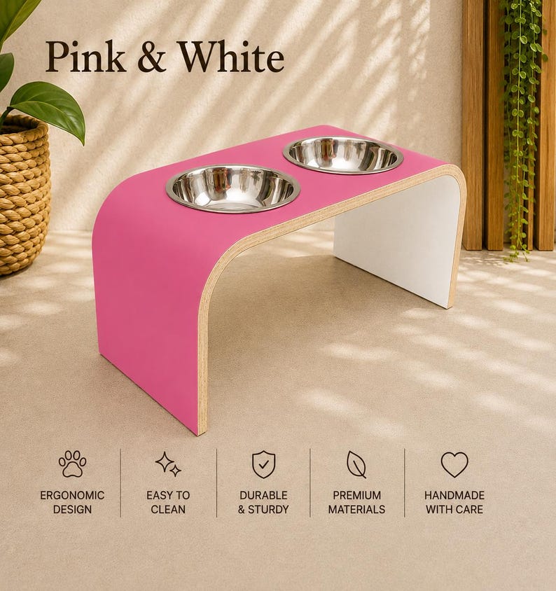 Pink and white raised dog bowl stand with stainless steel bowls, handmade elevated wooden pet feeder in a bright contemporary home, modern feeding station for dogs and cats.