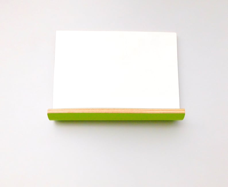 Front view of a whiteboard with green on the reverse in landscape form with a shelf ideal for pens or keys with a natural wood trim on a wall.