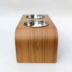 End view of an elevated cat/dog feeder easy to clean in a walnut finish holding 2 stainless steel bowls and natural wood trim on a white backgrounds.