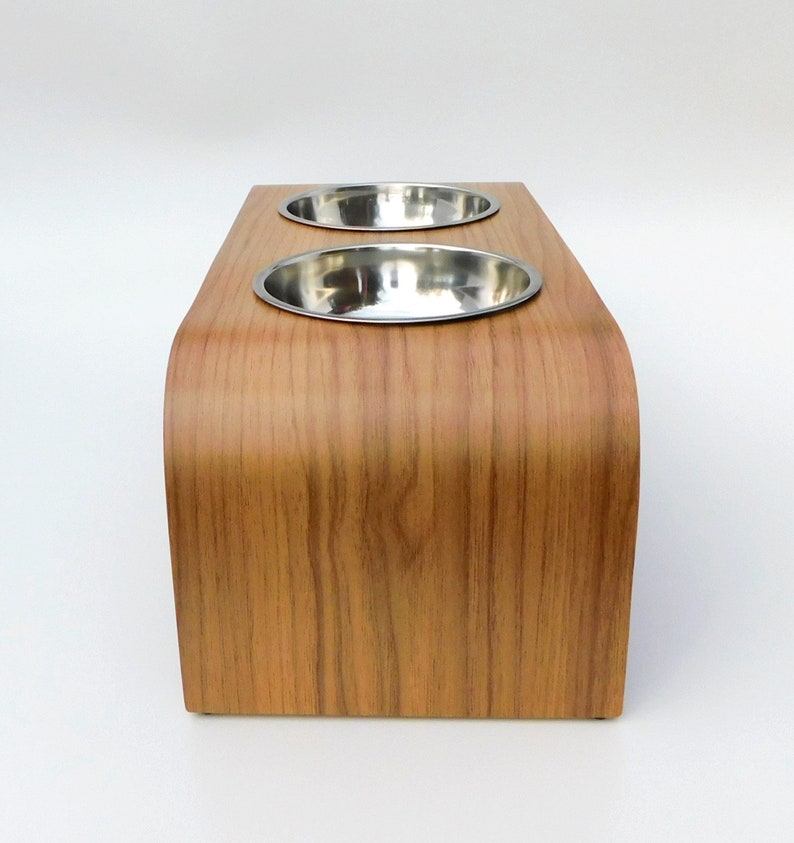 End view of an elevated cat/dog feeder easy to clean in a walnut finish holding 2 stainless steel bowls and natural wood trim on a white backgrounds.