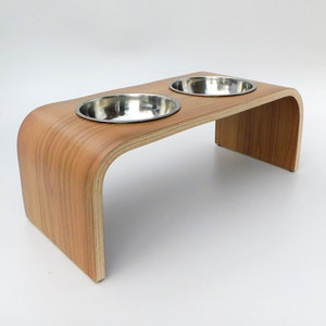 Angled view of an elevated easy to clean pet feeder in a walnut finish holding 2 stainless steel bowls and natural wood trim on a white background.