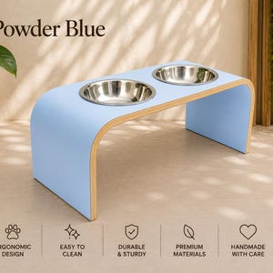Powder blue raised wooden dog bowl stand with stainless steel bowls, handmade elevated pet feeder in a bright contemporary home, ergonomic feeding station for dogs and cats.
