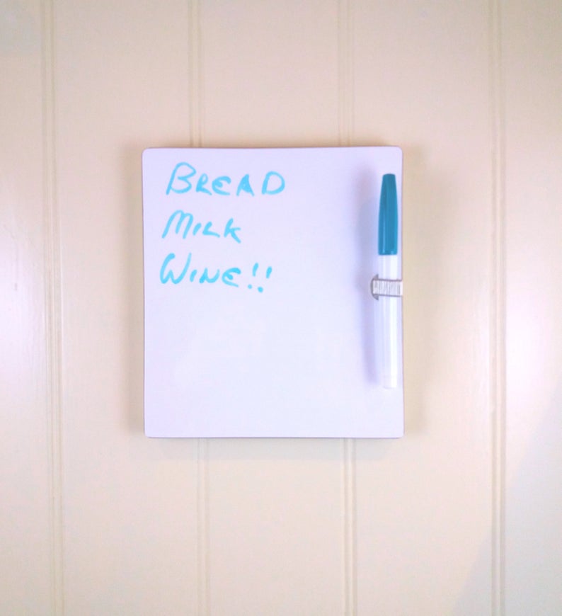 Front view of small whiteboard / message board / fridge board attached by Velcro pads, pen and pen holder included with a natural wood trim on a white background.