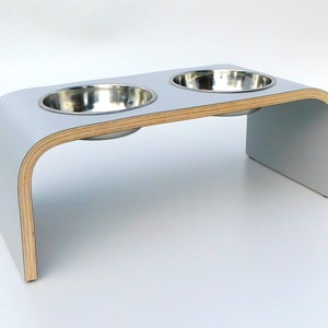 Angled view of Light grey double raised pet feeder with stainless steel bowls and natural wood edge finish.