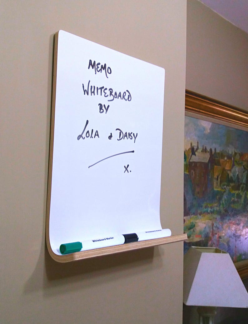 Angled view of dry erase whiteboard with a shelf and a natural wood trim on a wall.