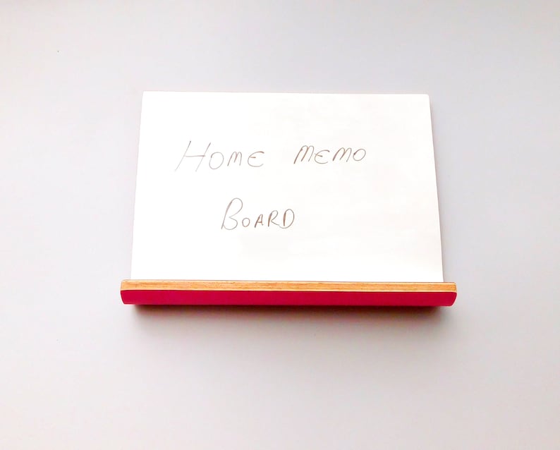 Front view of a whiteboard with pink on the reverse in landscape form with a shelf ideal for pens or keys with a natural wood trim on a wall.