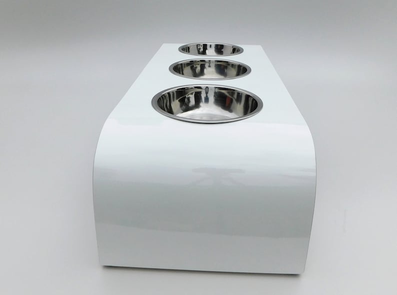 End view of our triple bowl raised dog feeder in a white gloss finish on a white background with three stainless steel bowls and showing the natural wood edge finish.