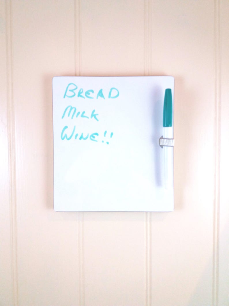 Front view of small whiteboard / message board / fridge board attached by Velcro pads, pen and pen holder included with a natural wood trim on a white background.