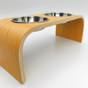 Angled view of Light oak double raised pet feeder with stainless steel bowls and natural wood edge finish.