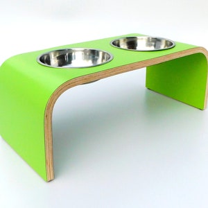 Angled view of Green double raised pet feeder with stainless steel bows and natural wood edge finish.