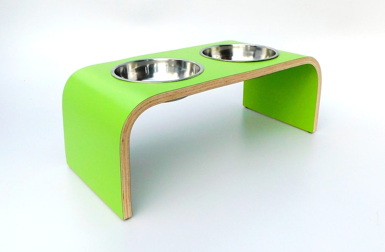 Angled view of Green double raised pet feeder with stainless steel bows and natural wood edge finish.