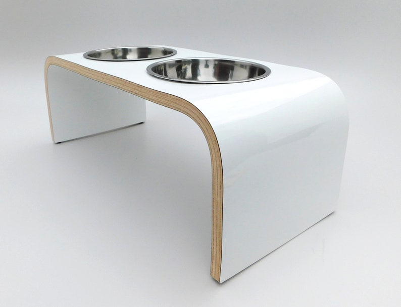 Angled view of White gloss double raised dog feeder with stainless steel bowls and natural wood edge finish.