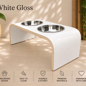 White gloss elevated dog bowl stand with two stainless steel bowls, handmade raised wooden pet feeder in a bright modern home, stylish feeding station for dogs and cats.