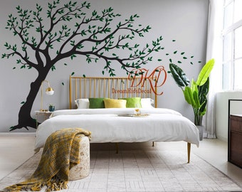 May include: A large black tree wall decal with green leaves is applied to a light gray wall above a gold metal bed frame. The decal features a sprawling branch design with scattered leaves. The text DKD DreamKidsDecol is visible.
