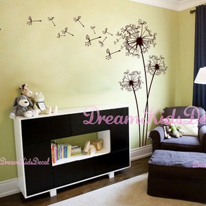 K&ouml;nnte beinhalten: Ein Kinderzimmer mit einem schwarz-wei&szlig;en B&uuml;cherregal, einem braunen Sessel und einem braunen Hocker. Die Wand ist hellgr&uuml;n gestrichen und zeigt ein gro&szlig;es Wandtattoo in Form eines L&ouml;wenzahns mit kleineren L&ouml;wenzahn-Wandtattoos, die um ihn herum verstreut sind. Der Text "Dream Kids Decal" ist auf dem Bild zu sehen.