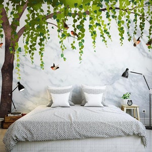 May include: A white bed with a black and white patterned duvet cover and two white pillows. The wall behind the bed has a mural of a green tree with birds and a marble pattern.