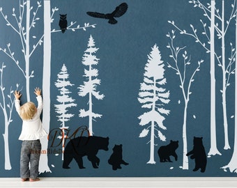 May include: Black silhouette wall decals of a forest scene with trees, an owl, and bears. The decals are on a blue wall.