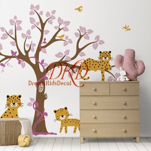 Op de afbeelding: Een bruine boom met roze bladeren en een wijnstok, met drie gele en bruine luipaarden, twee vogels en de tekst "Dream KidsDecal".
