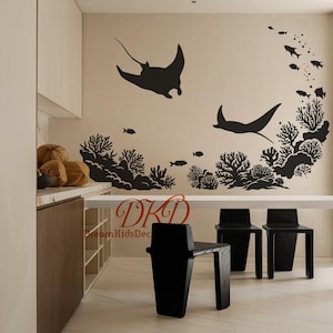 Puede incluir: Vinilo decorativo negro con una escena marina con mantarrayas, corales y peces. El diseño incluye el texto "DKD DreamKidsDec". El vinilo se aplica a una pared beige en una habitación con sillas negras y una mesa blanca.