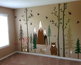 May include: A brown bear, two rabbits, and a mountain range with snow-capped peaks are featured in this woodland-themed wall decal set. The decal set also includes trees, birds, and leaves. The decal set is perfect for a nursery or child's room.