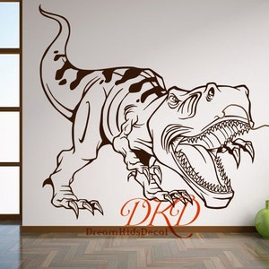 Może przedstawiać: Brązowa naklejka ścienna z Tyrannosaurusem Rexem z ostrymi zębami i pazurami oraz tekstem "DreamKidsDecal". Dinozaur przedstawiony jest w dynamicznej pozie, ze szczeg&oacute;łowym obrysem i wzorem w plamki na grzbiecie.