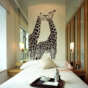 K&ouml;nnte beinhalten: Ein schwarz-wei&szlig;es Wandtattoo mit zwei sich k&uuml;ssenden Giraffen. Die Giraffen befinden sich in einem Schlafzimmer mit einem wei&szlig;en Bett und einem wei&szlig;en Nachttisch.