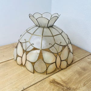 May include: A dome-shaped lamp shade constructed from translucent, off-white shell segments held together by thin metal framing. The design features a scalloped top edge and a repeating butterfly motif integrated into the lower perimeter.