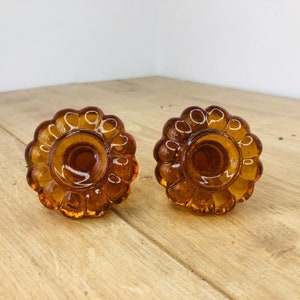 May include: Two amber glass knobs with a textured, flower-like design. The knobs are circular and have a smooth, shiny finish.