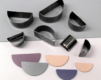 May include: A set of six metal half-circle leather punches and six leather pieces cut with the punches. The leather pieces are in purple, gray, and peach.