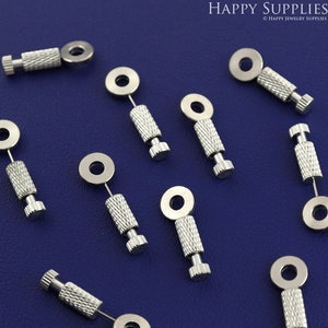 May include: Ten silver-toned jewelry making tools with a small ring at the top and a threaded shaft. The tools are arranged on a blue surface.